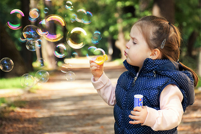 young girl blowing bubbles